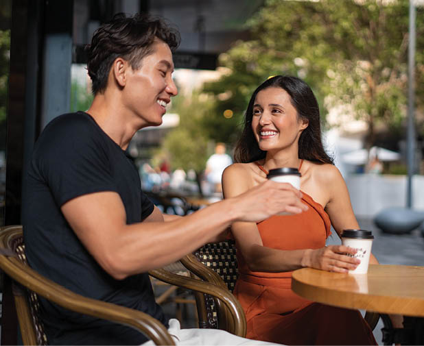 A man and woman sitting at a table with a coffee cup in front of them. Description generated by AI