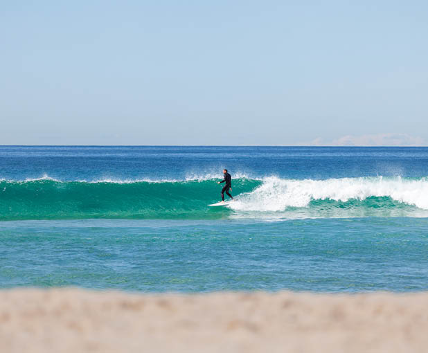 A man in a black wetsuit is surfing on a wave. Description generated by AI
