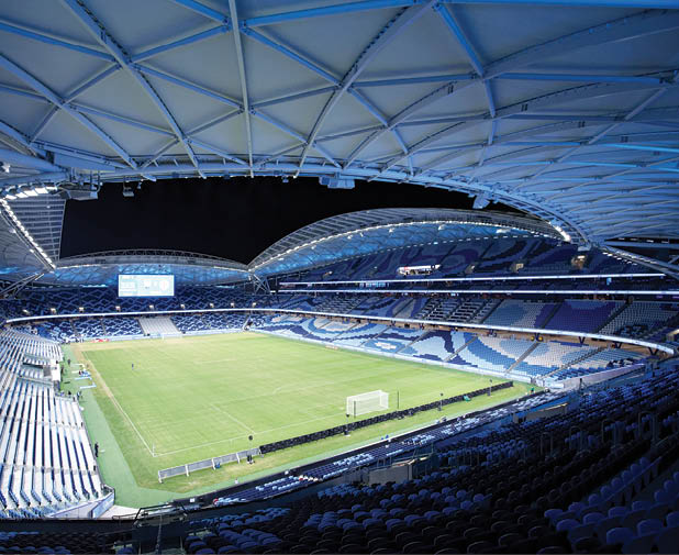 A large stadium with a blue roof and a green field. Description generated by AI