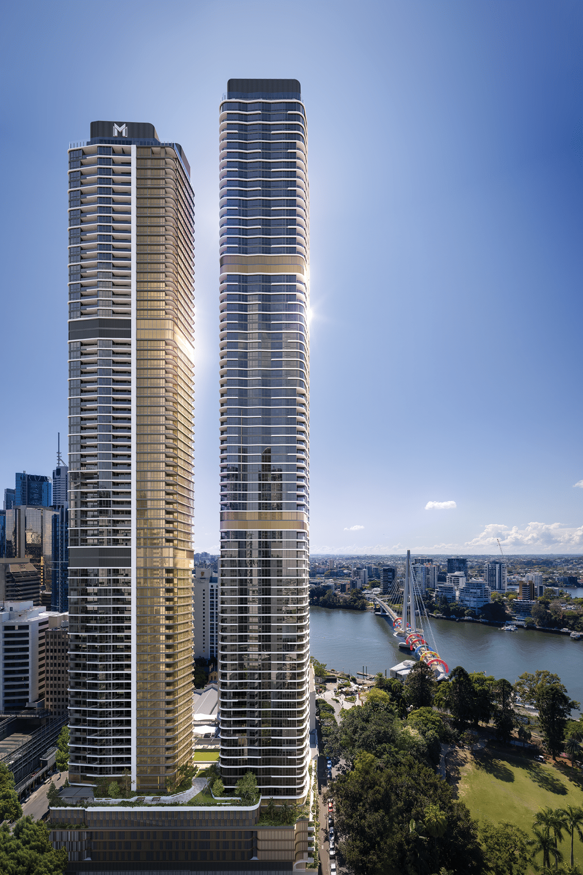 Two modern high-rise buildings stand side by side near a river with a cityscape and park visible in the background under a clear blue sky. Description generated by AI