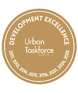 A gold circular emblem with the text Development Excellence around the top edge, Urban Taskforce Australia in the center, and years 2011, 2013, 2014, 2015, 2016, 2021, 2024, and 2025 listed along the bottom edge. Description generated by AI
