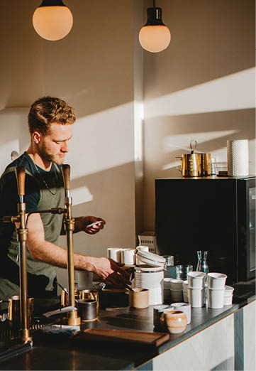 A man is standing in front of a counter with a coffee maker. Description generated by AI