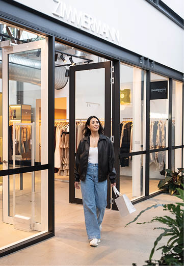A woman is walking in front of a store window. Description generated by AI